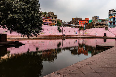 Reflection of building in lake against sky in city