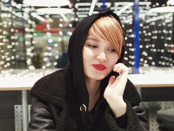 Beautiful woman wearing hood clothing while sitting at restaurant