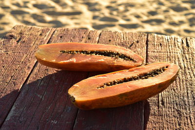 Fresh cut papaya on rustic wood table morning at seashore beach