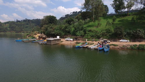 People on boat moored by river against sky