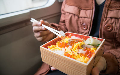 Midsection of woman eating food in vehicle