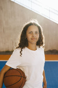 Pre-adolescent girl with basketball at sports court