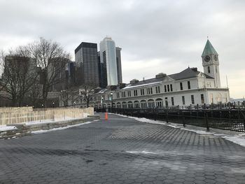 Road by buildings against sky during winter