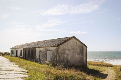 Built structure on beach by sea against sky