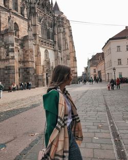 Full length of woman with umbrella against buildings in city