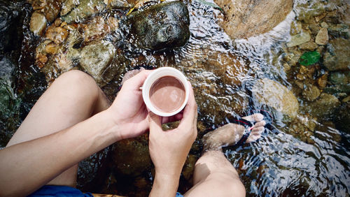 Low section of man holding rock in water