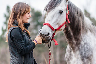 Side view of woman with horse standing on field