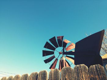 Low angle view of fence and traditional windmill against clear sky