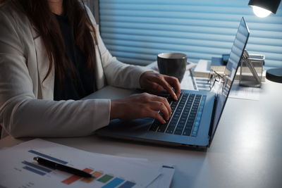 Rear view of woman using laptop on table