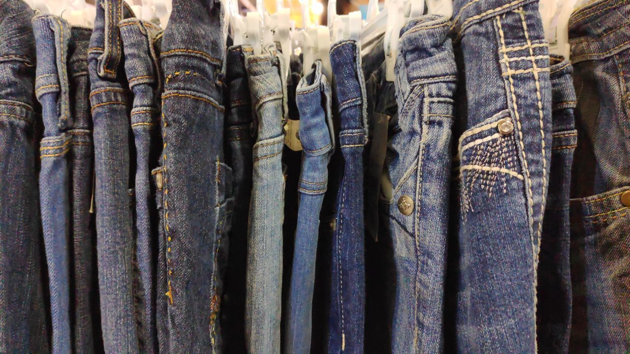 FULL FRAME SHOT OF CLOTHES HANGING IN MARKET STALL