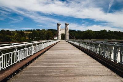 Footbridge leading towards bridge against sky