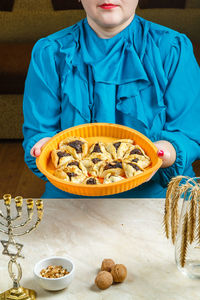 Gomentashi cookies, traditional for the jewish holiday of purim, on a tray in the hands of a woman