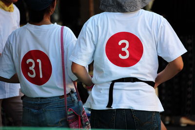 Rear view of woman wearing t-shirts with numbers standing outdoors