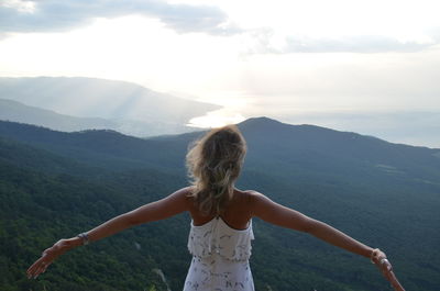 Rear view of wife standing on mountain against sky