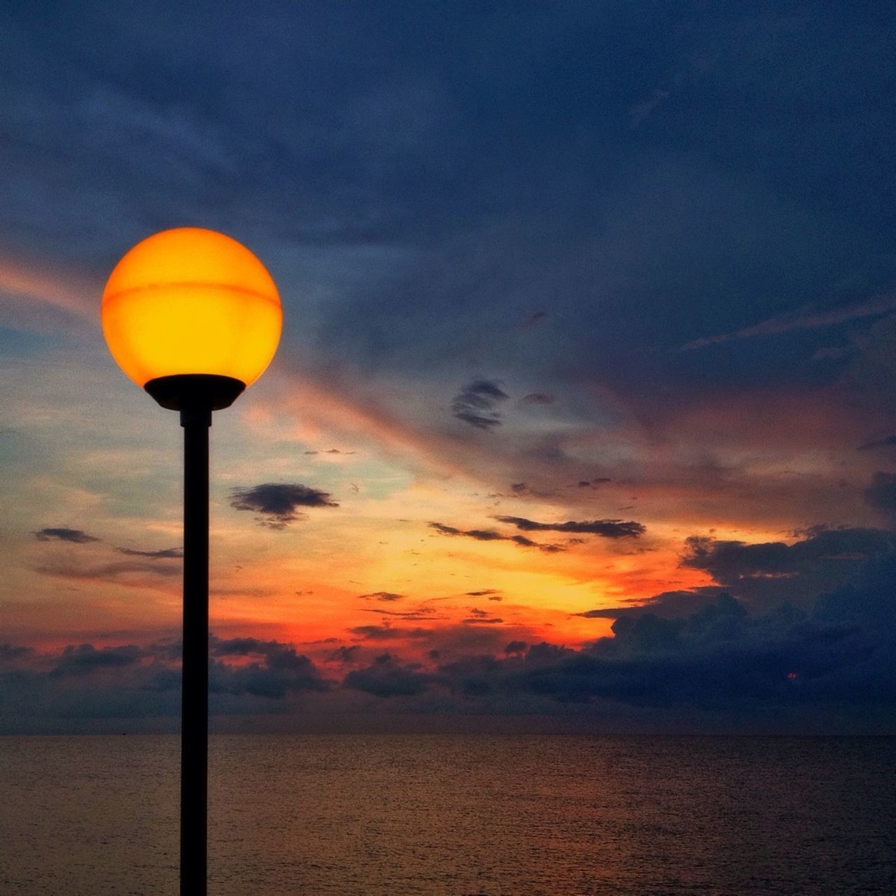 sunset, sky, orange color, scenics, beauty in nature, tranquility, tranquil scene, cloud - sky, street light, nature, idyllic, lighting equipment, sea, dramatic sky, silhouette, cloud, water, dusk, horizon over water, illuminated