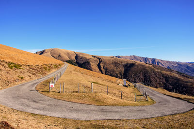 Scenic view of mountain road against clear blue sky