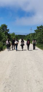 Rear view of people walking against sky