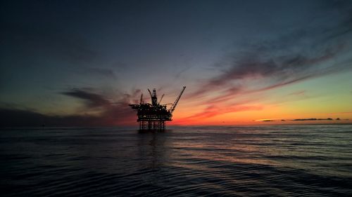 Silhouette ship in sea against sky during sunset