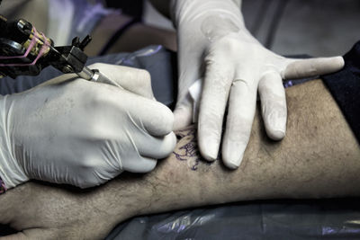 Cropped image of artist making tattoo on customers hand