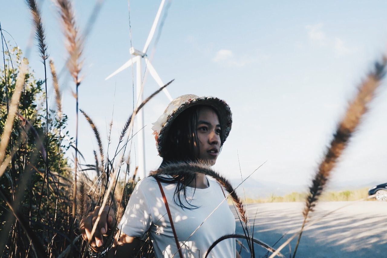 sky, real people, nature, fuel and power generation, young adult, one person, environmental conservation, plant, turbine, renewable energy, wind turbine, day, lifestyles, environment, alternative energy, leisure activity, portrait, young women, focus on foreground, outdoors, hairstyle, beautiful woman