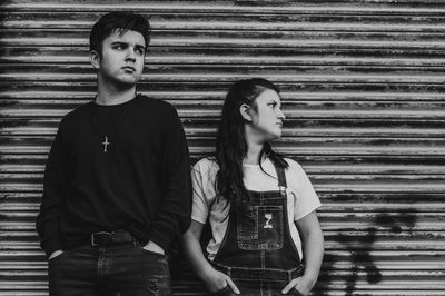 Portrait of a young couple standing against wall