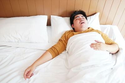 High angle view of man sleeping on bed at home