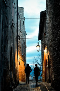 Rear view of people walking on street amidst buildings in city