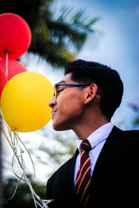 Businessman by balloons against sky