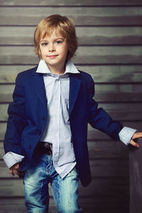 Portrait of boy standing against wall