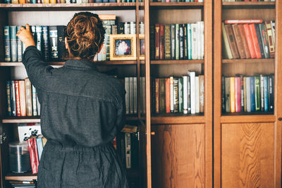 Rear view of woman standing in shelf