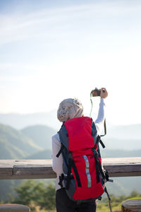 Rear view of people standing on mountain against sky