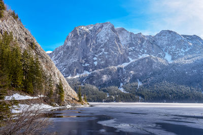 Frozen lake by snowcapped mountains against sky