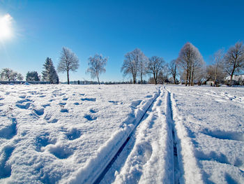 Snow covered field against blue sky