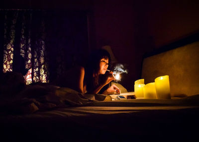 Woman smoking cigarette in illuminated room