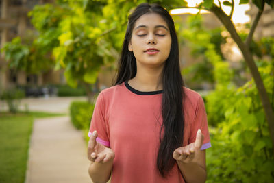 Portrait of young woman standing against plants