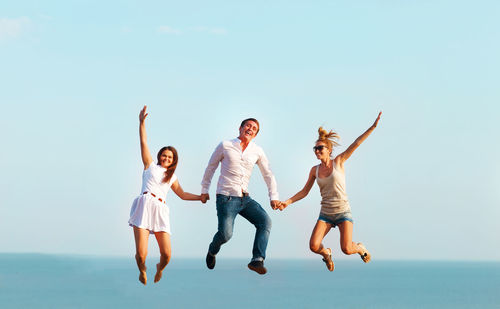 Full length of friends enjoying at sea against sky