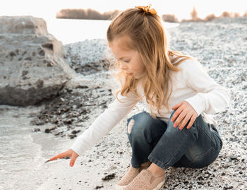 Side view of young woman sitting at beach