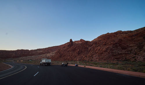 Road by mountain against clear blue sky