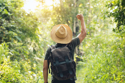 Rear view of person wearing hat standing by trees