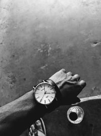 Close-up of hand holding clock against wall