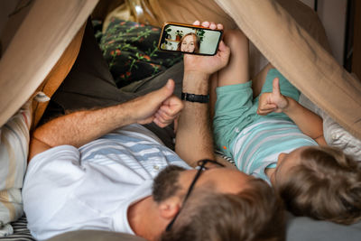 Woman using mobile phone while lying on bed at home