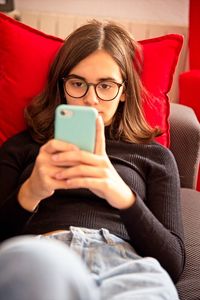 Young woman using mobile phone while sitting on sofa