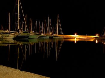 Illuminated boats moored in sea against sky at night