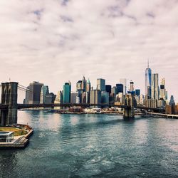 City at waterfront against cloudy sky