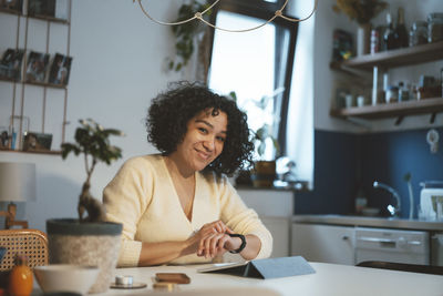 Smiling woman with tablet pc using smart watch at home