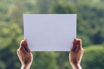 Close-up of hand holding paper against blurred background