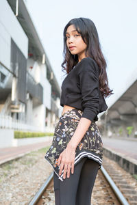 Portrait of beautiful young woman standing against sky