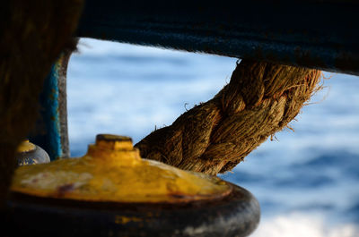 Close-up of rusty metal by wood against sky