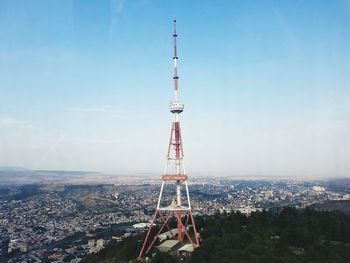 Communications tower in city against sky