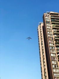 An airplane flying next to an apartment building